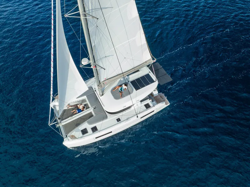 Slide: The Image of Aerial view of 2025 Lagoon 38 catamaran sailing on clear blue ocean waters. - 0