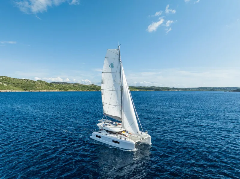 Slide: The Image of Sailing catamaran Lagoon 38, 2025 model, cruising on blue ocean under clear sky. - 4