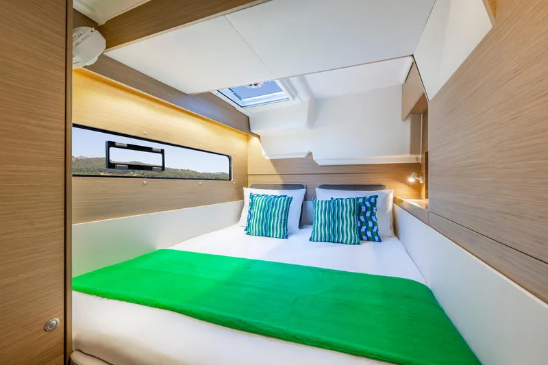 Slide: The Image of Modern cabin interior of 2025 Lagoon 38 catamaran with green bedding and striped pillows. - 44