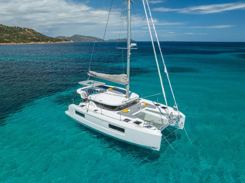 Slide: The Image of 2025 Lagoon 38 catamaran sailing in clear turquoise waters, under a partly cloudy sky. - 72