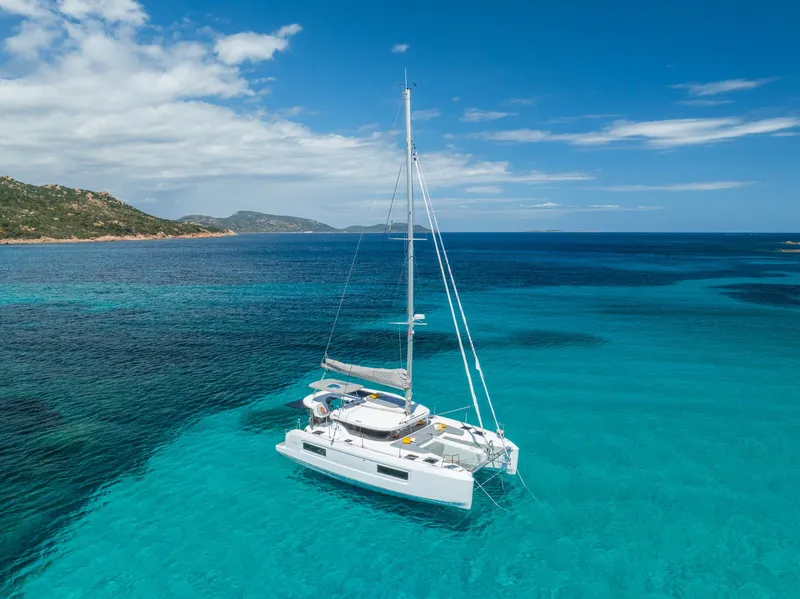 Slide: The Image of 2025 Lagoon 38 catamaran sailing in clear turquoise waters near a scenic coastline. - 73