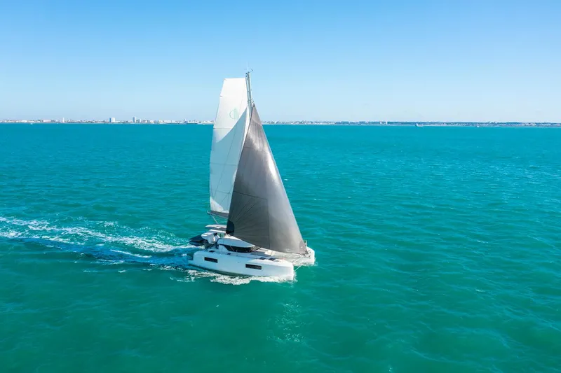 Slide: The Image of 2025 Lagoon 38 sailing catamaran gliding on turquoise ocean waters under clear blue sky. - 78