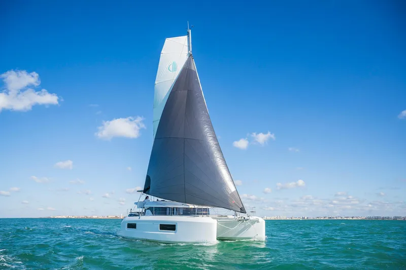 Slide: The Image of 2025 Lagoon 38 catamaran sailing on open sea under clear blue sky. - 83