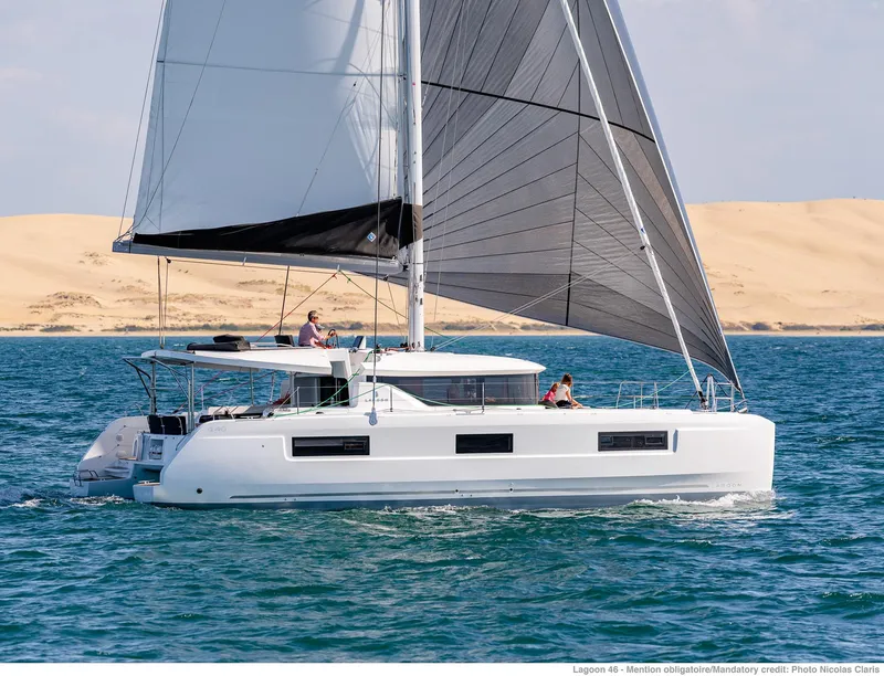 Slide: The Image of 2025 Lagoon 46 ICONIC catamaran sailing on blue ocean near sandy dunes. - 4