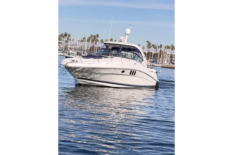 Slide: The Image of 2008 Sea Ray 40 Sundancer yacht on calm water, with marina and palm trees in background. - 2