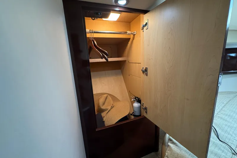 Slide: The Image of Open wooden closet in 2008 Sea Ray 40 Sundancer yacht, featuring hangers and a hat. - 54