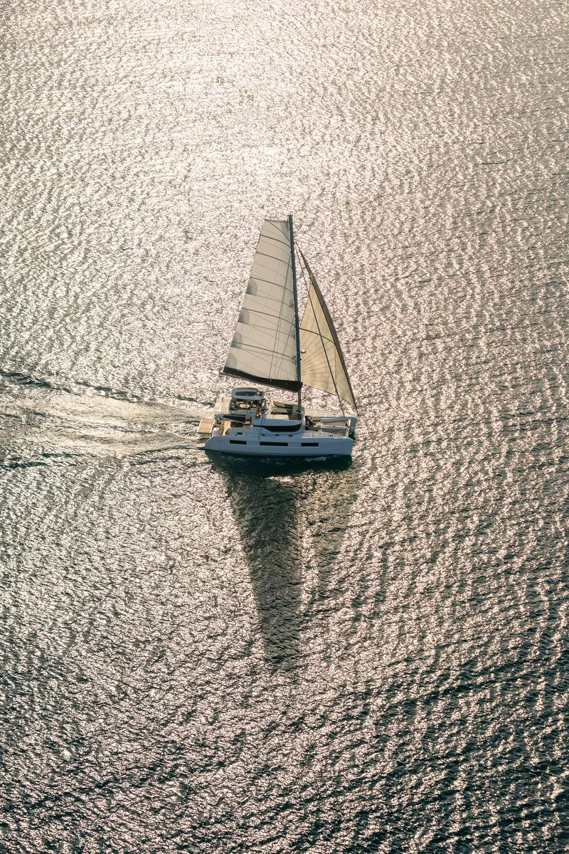 Slide: The Image of Aerial view of 2025 Lagoon 51 ICONIC sailing on shimmering water. - 17