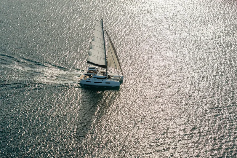 Slide: The Image of Aerial view of 2025 Lagoon 51 ICONIC sailing on shimmering water. - 18