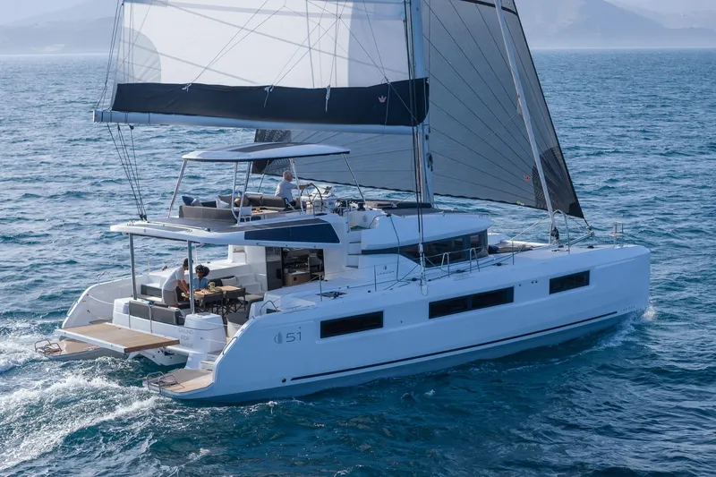 Slide: The Image of 2025 Lagoon 51 ICONIC catamaran sailing on open sea, showcasing sleek design and spacious deck. - 2