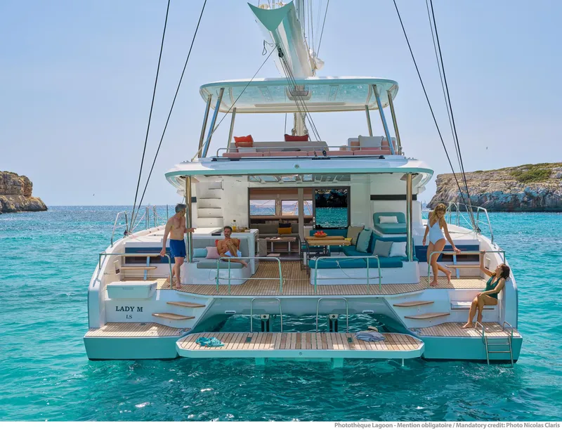 Slide: The Image of 2025 Lagoon 55 yacht on turquoise water, featuring spacious deck and lounging area. - 8