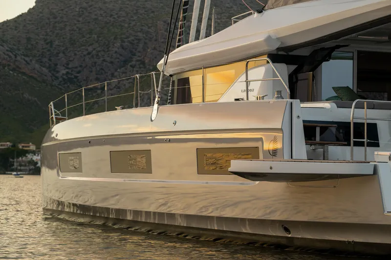 Slide: The Image of 2025 Lagoon 60 yacht on calm water with scenic mountain backdrop. - 6