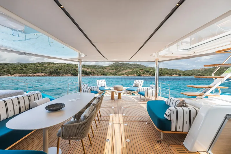 Slide: The Image of Luxurious 2025 Lagoon Eighty 2 yacht deck with elegant seating, overlooking serene blue waters and lush coastline. - 12
