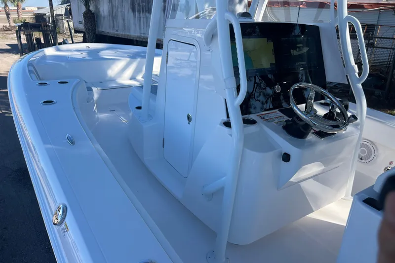 Slide: The Image of 2026 Contender 29 Bay boat interior with seating and console, parked outdoors. - 15