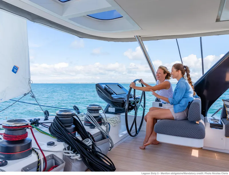Slide: The Image of Two people sailing on a 2025 Lagoon SIXTY 5 catamaran, enjoying the open sea. - 5