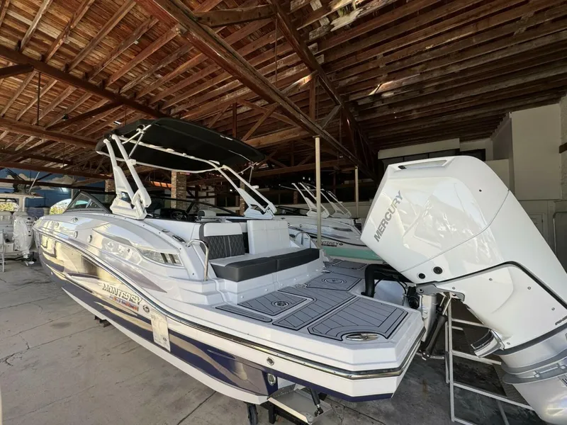 Slide: The Image of 2024 Monterey M-65 boat with Mercury engine in a wooden-roofed storage area. - 1