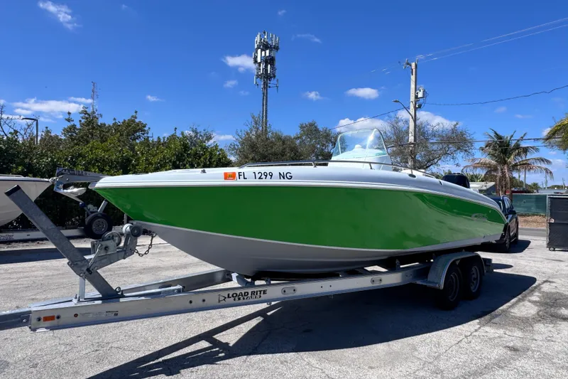 Slide: The Image of 2006 Baja 250 Sportfish boat on trailer, vibrant green hull, clear blue sky background. - 2