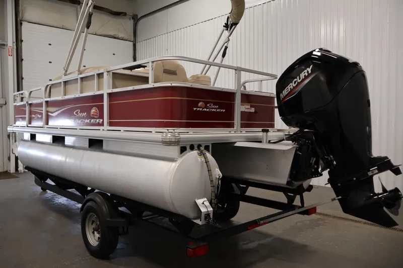 Slide: The Image of 2021 Sun Tracker Bass Buggy 18 DLX pontoon boat with Mercury outboard motor in a garage. - 7