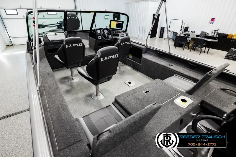 Slide: The Image of 2023 Lund 1875 Impact XS boat interior with seating and dashboard in a showroom. - 10