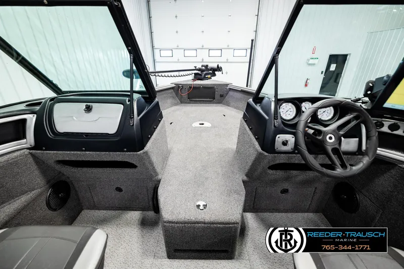 Slide: The Image of 2023 Lund 1875 Impact XS boat interior with steering wheel and dashboard in showroom. - 23