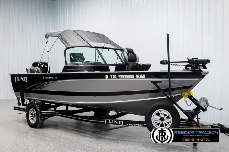 Slide: The Image of 2023 Lund 1875 Impact XS boat on trailer, displayed indoors at Reeder-Trausch Marine. - 3