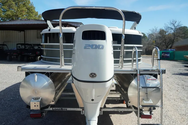 Slide: The Image of 2026 Trifecta 24E CS pontoon boat with powerful 200 engine, parked outdoors. - 10