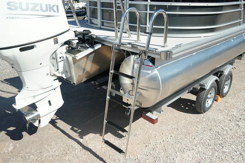 Slide: The Image of 2026 Trifecta 24E CS pontoon boat with Suzuki outboard motor and ladder on trailer. - 48