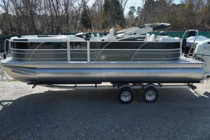 Slide: The Image of 2026 Trifecta 24E CS pontoon boat on trailer, parked outdoors. - 5