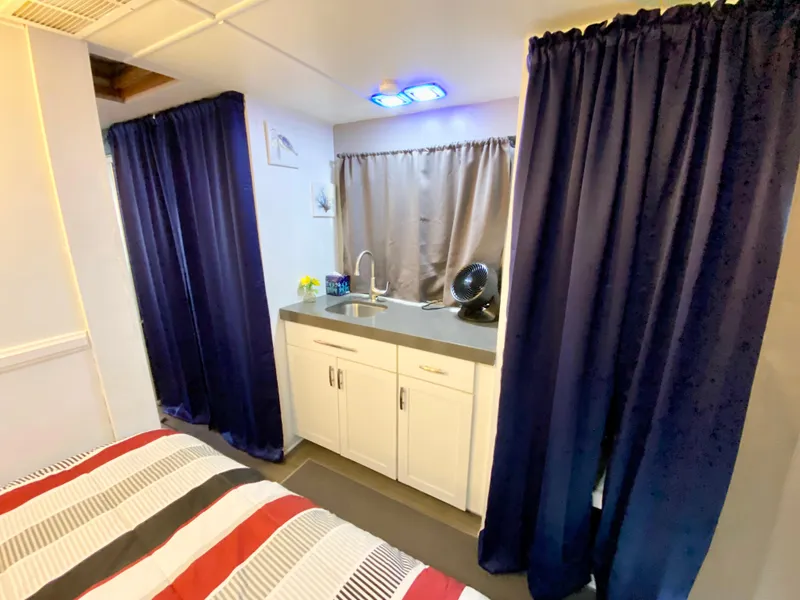 Slide: The Image of Interior of 1988 Three Buoys 4412 with kitchenette, bed, and blue curtains. - 24