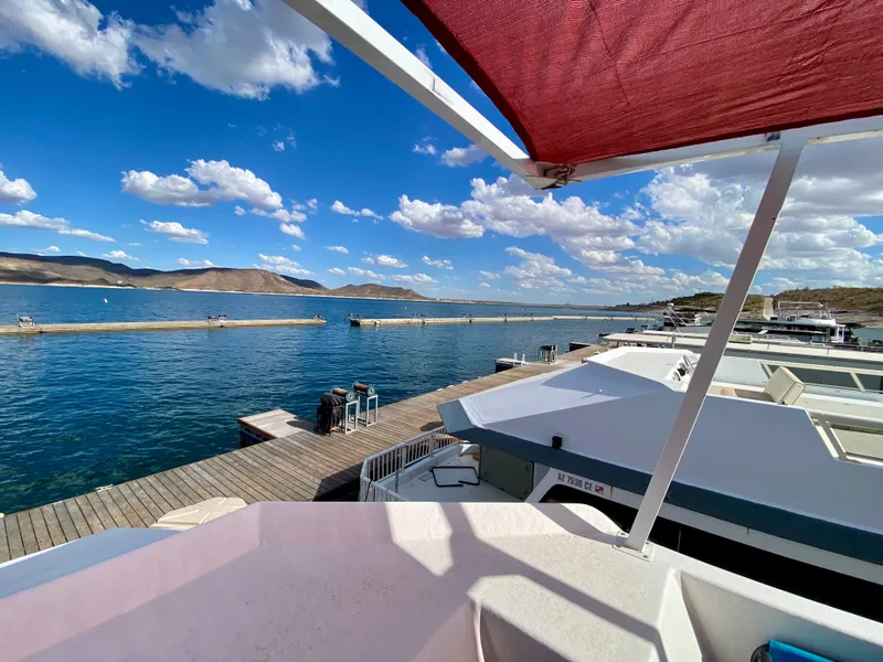 Slide: The Image of Houseboat docked by a scenic lake under a blue sky, Three Buoys 4412, 1988 model. - 35