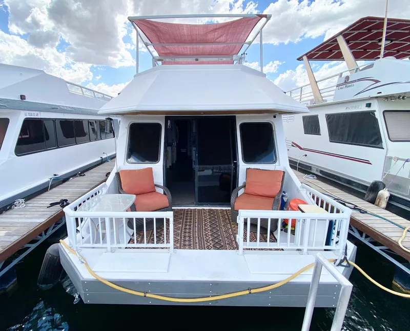 Slide: The Image of 1988 Three Buoys 4412 houseboat docked, featuring a cozy deck with seating. - 7