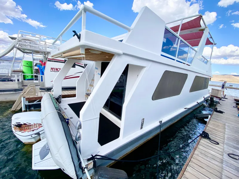 Slide: The Image of 1988 Three Buoys 4412 houseboat docked, featuring modern design and spacious upper deck. - 9