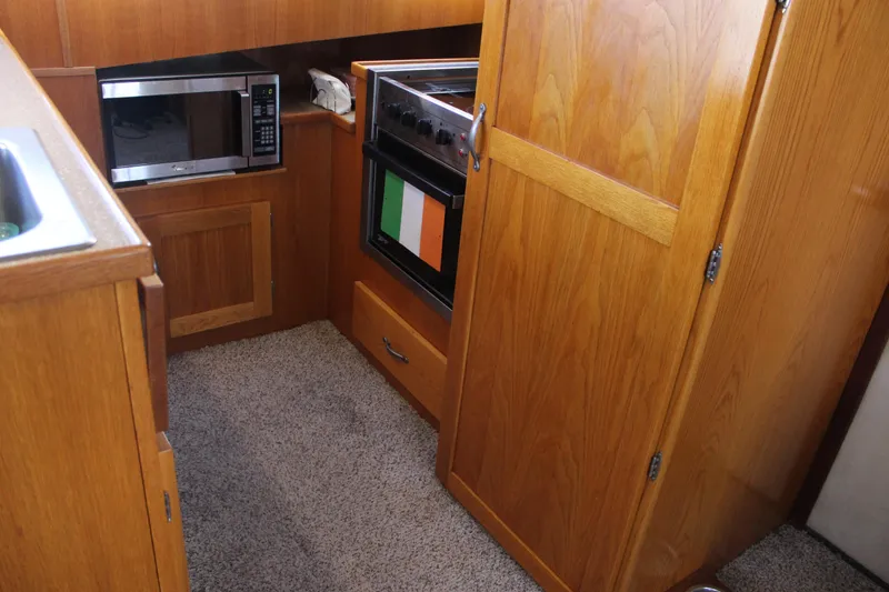 Slide: The Image of 1987 Chris-Craft 381 Catalina kitchen with wooden cabinetry, microwave, and oven. - 22