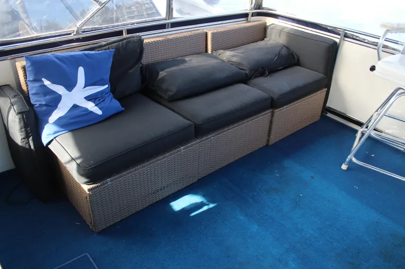 Slide: The Image of 1987 Chris-Craft 381 Catalina interior with wicker sofa, blue starfish pillow, and blue carpet. - 4