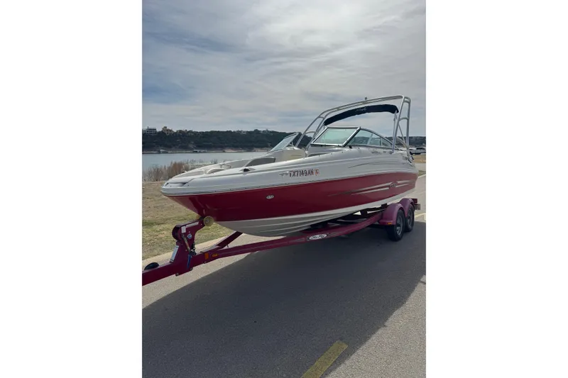 Slide: The Image of 2007 Sea Ray 200 Sundeck boat on trailer by a lakeside road. - 2
