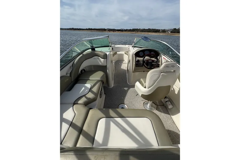 Slide: The Image of 2007 Sea Ray 200 Sundeck interior with seating and steering, on calm water. - 7