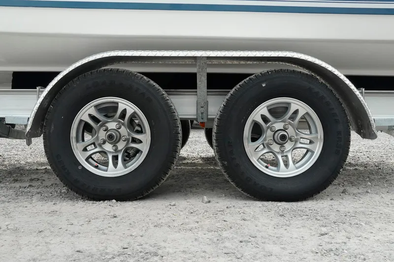 Slide: The Image of Trailer wheels of a 2026 Tidewater 232 LXF boat on gravel surface. - 52