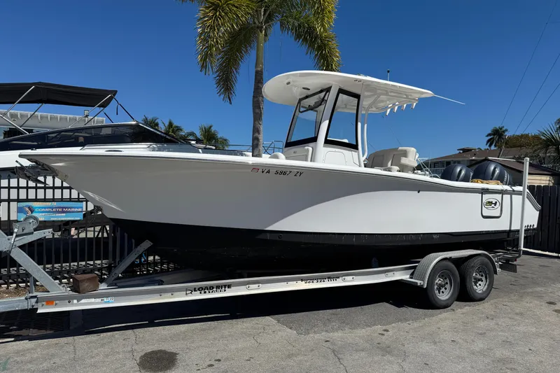 Slide: The Image of 2022 Sea Hunt Gamefish 25 boat on trailer, parked near palm trees. - 0