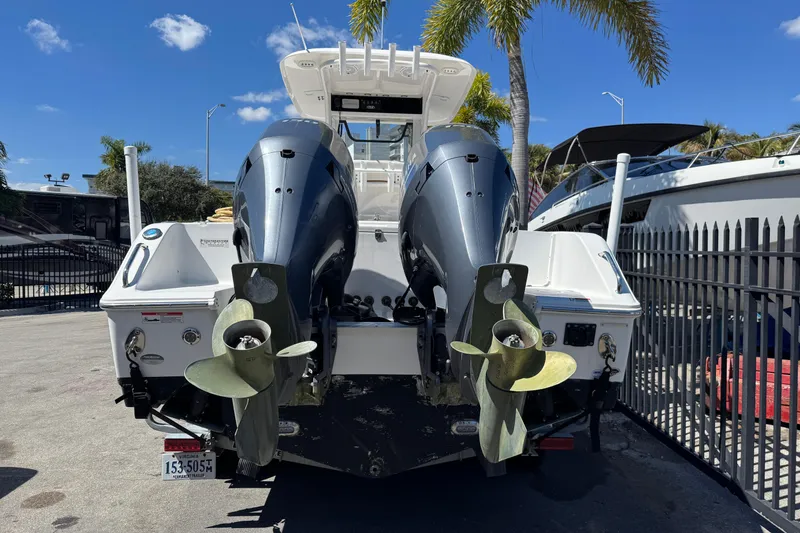 Slide: The Image of 2022 Sea Hunt Gamefish 25 boat with dual outboard motors, docked under palm trees. - 27