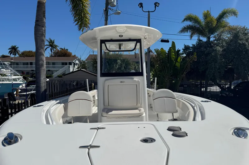 Slide: The Image of 2022 Sea Hunt Gamefish 25 boat, white exterior, docked with palm trees in the background. - 29