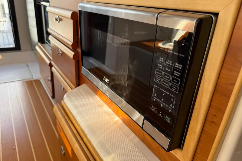 Slide: The Image of Microwave in 2022 Cutwater C-32 CB boat kitchen with wooden cabinetry. - 22