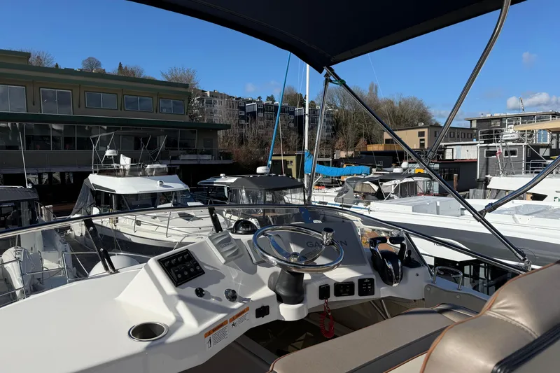 Slide: The Image of 2022 Cutwater C-32 CB boat helm with marina view, featuring modern controls and steering. - 27