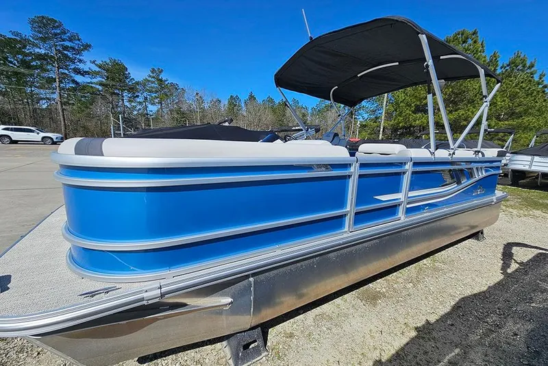 Slide: The Image of 2026 SunCatcher Select 22C pontoon boat with blue exterior and canopy, parked outdoors. - 1