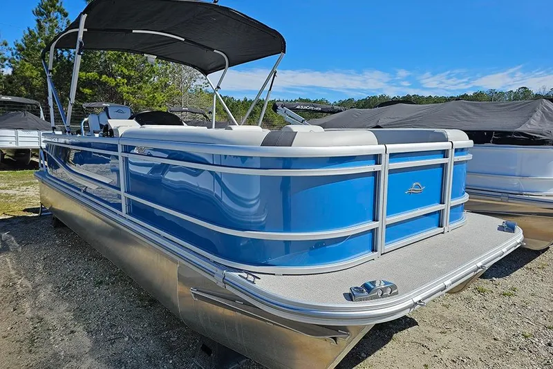 Slide: The Image of 2026 SunCatcher Select 22C pontoon boat with blue exterior and canopy, parked outdoors. - 3
