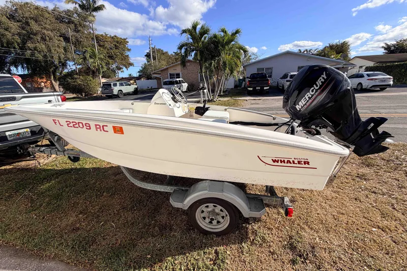 Slide: The Image of 2016 Boston Whaler 130 Super Sport boat on trailer, parked outdoors. - 0