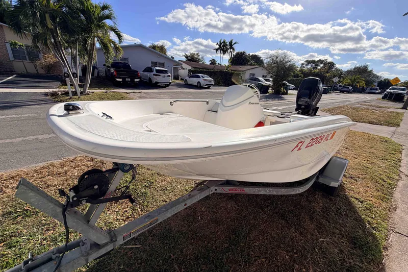 Slide: The Image of 2016 Boston Whaler 130 Super Sport boat on trailer, parked in residential area. - 1