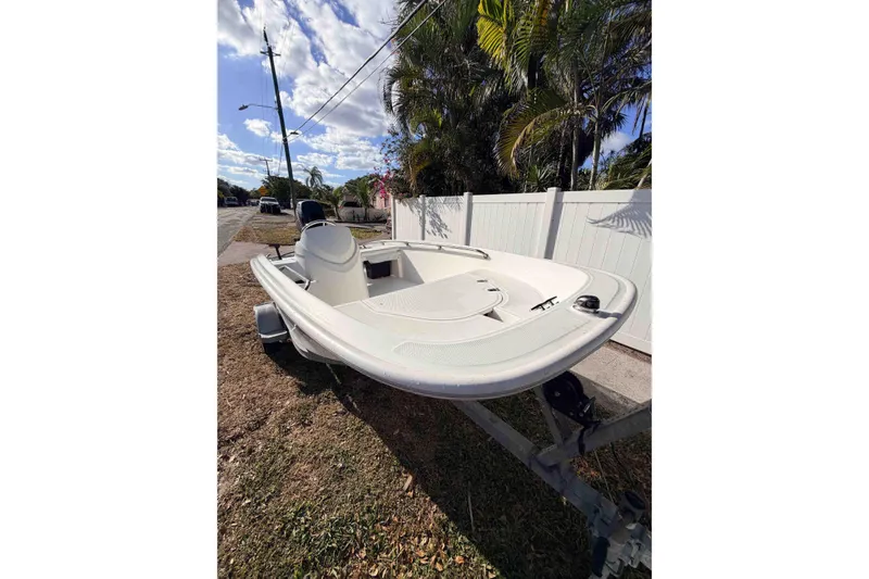 Slide: The Image of 2016 Boston Whaler 130 Super Sport boat on trailer, parked near palm trees. - 6