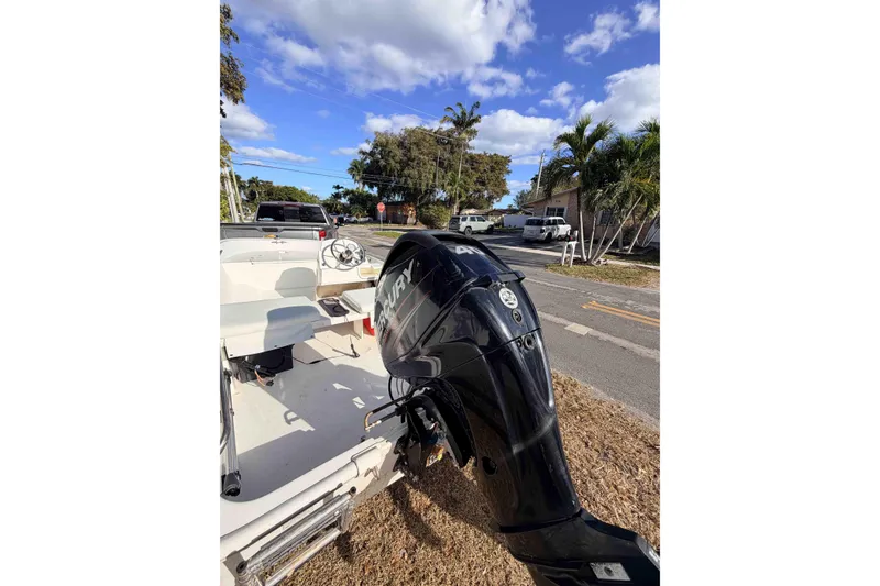 Slide: The Image of 2016 Boston Whaler 130 Super Sport boat with Mercury outboard motor, parked on a sunny street. - 7