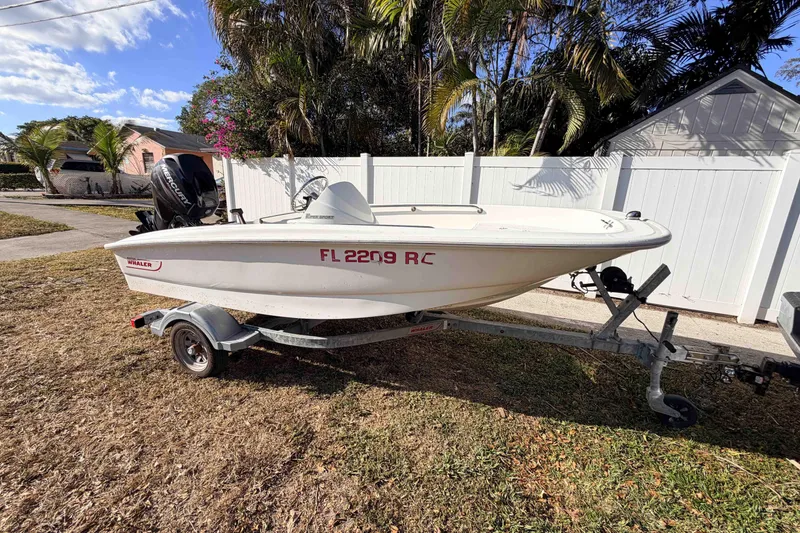 Slide: The Image of 2016 Boston Whaler 130 Super Sport boat on trailer, parked in a residential yard. - 8