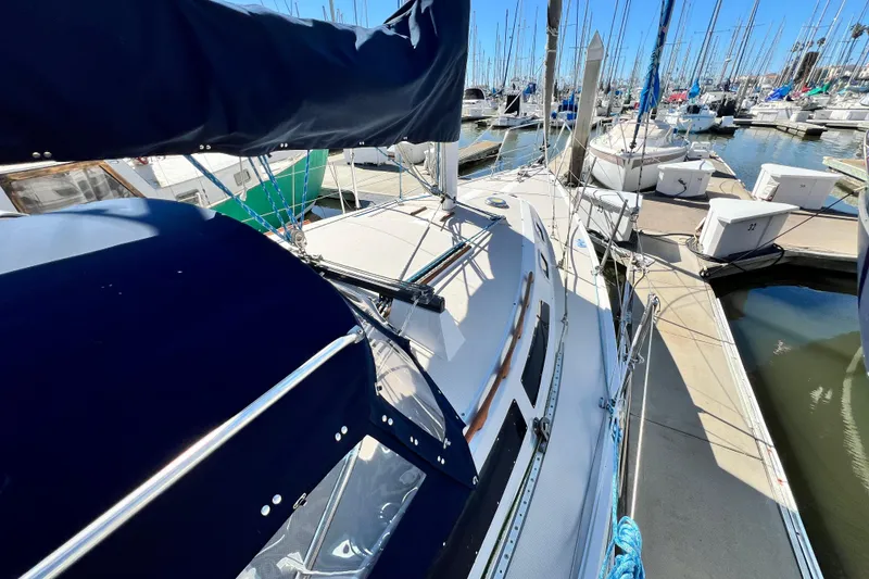 Slide: The Image of 1987 Catalina 30 MkII sailboat docked at marina, featuring blue canvas and sleek design. - 13