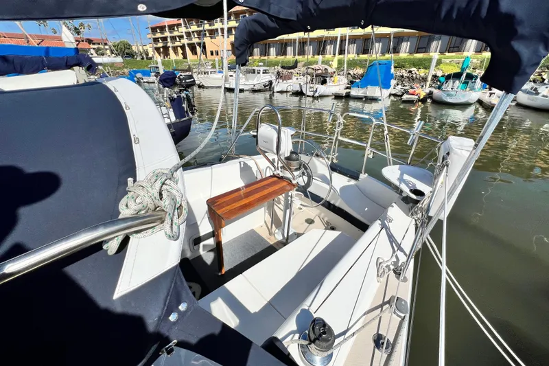 Slide: The Image of 1987 Catalina 30 MkII sailboat cockpit with marina view, featuring seating and steering wheel. - 15